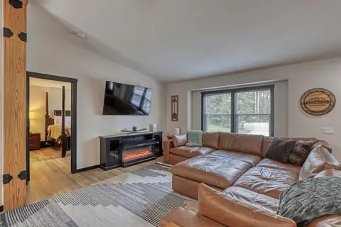 Living room with a leather sectional, an electric fireplace, and a wall-mounted TV