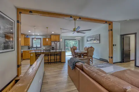 Living room sectional with the kitchen island and dining table beyond a timber beam