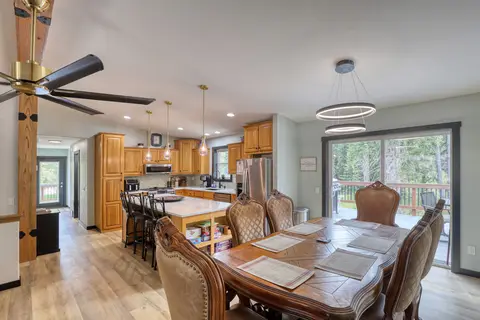 Carved wood dining table beside the kitchen island, with a sliding door to the deck