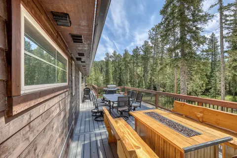 Long deck with a fire table between log benches and a dining table beyond