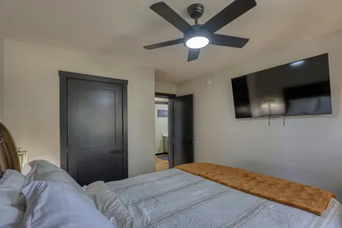 Queen bedroom with a wall-mounted TV across from the bed