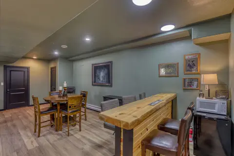 Bar counter with stools, a microwave, a mini fridge, and a pub table for four