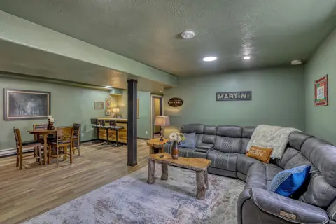 Lower-level family room with a gray reclining sectional and a log coffee table