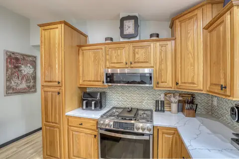 Gas range, microwave, and air fryer on white counters with a tile backsplash