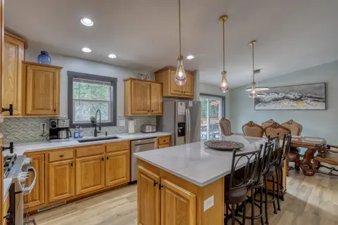 Kitchen with wood cabinets, a stainless fridge, and an island with four bar stools