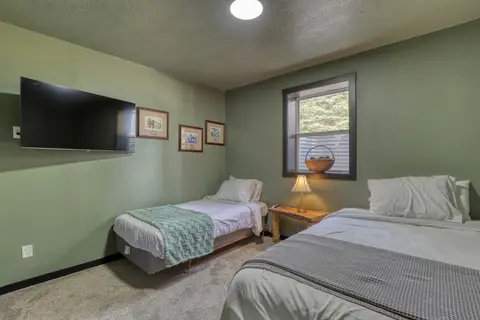 Lower-level bedroom with two beds and a wall-mounted TV