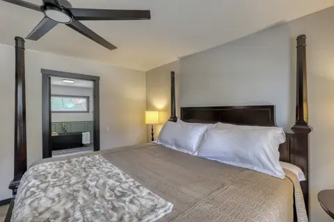 King four-poster bed with a doorway into the primary bathroom