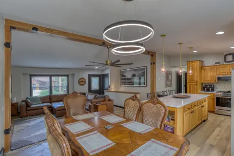Dining table set with placemats, with the living room and kitchen beyond