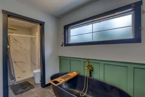 Black freestanding tub with a brass floor faucet and a bath caddy