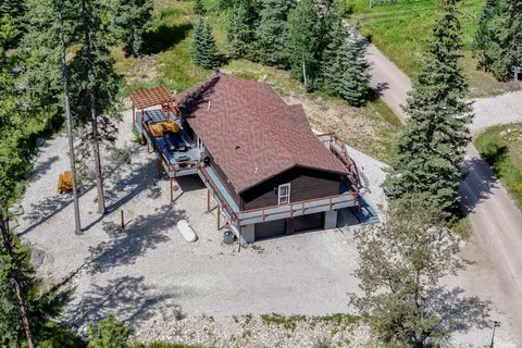 Aerial view of the house, its decks, and the gravel drive among the trees