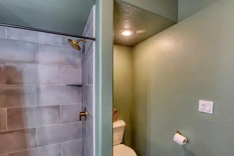 Tiled shower with a rain showerhead in the lower-level bathroom