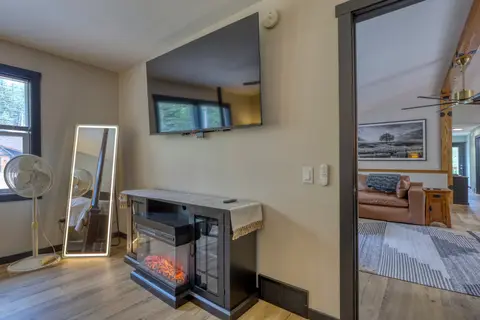Electric fireplace below a wall-mounted TV, with a lighted floor mirror