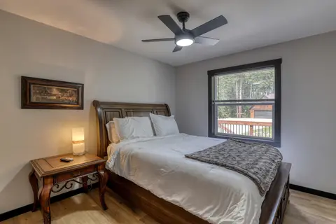 Queen bedroom with a sleigh bed, a bedside lamp, and a window to the deck