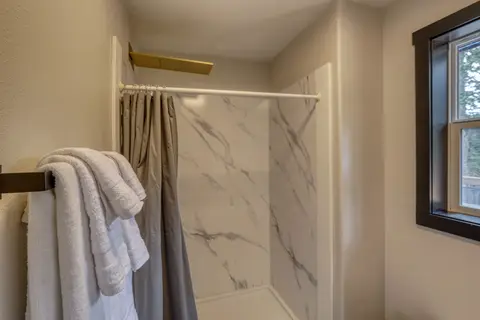Shower with marble-look walls and a brass rain showerhead
