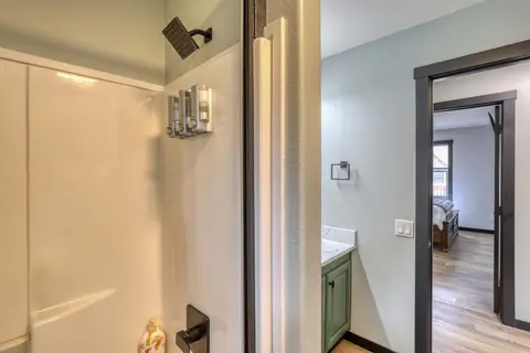 Shower with wall-mounted soap dispensers beside a green vanity