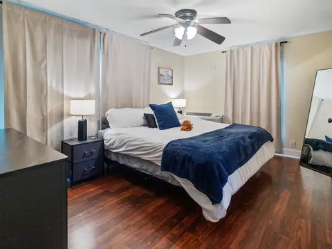 King bedroom with navy bedding, a ceiling fan, and curtained windows
