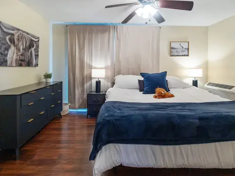 King bed with navy bedding beside a black dresser
