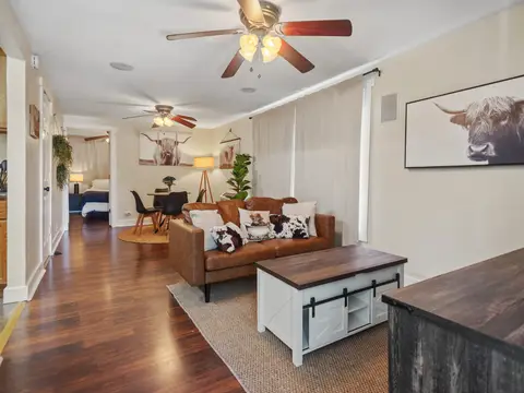 Living room with a leather sofa, looking down the hall to the bedroom