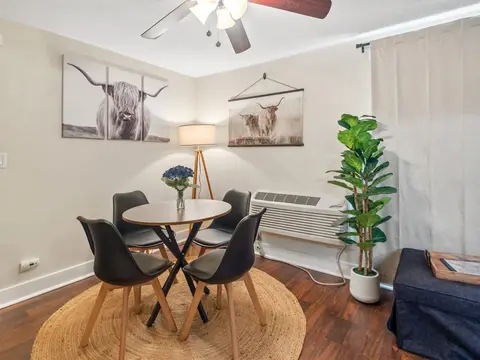 Round dining table with four black chairs by the window