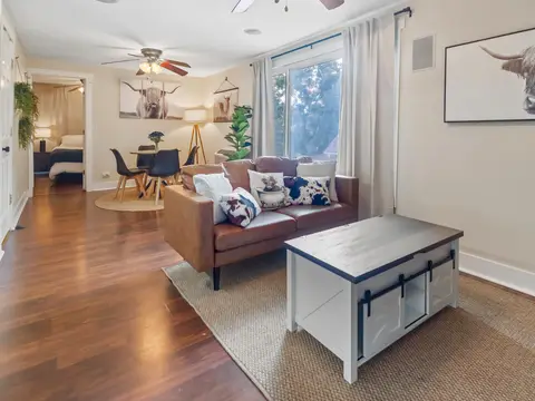 Living room with a leather sofa, opening to the dining nook and bedroom