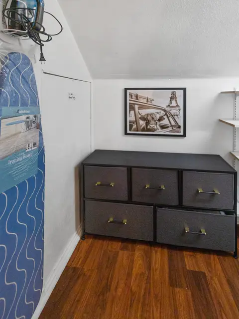 Dark dresser with an ironing board and a framed print