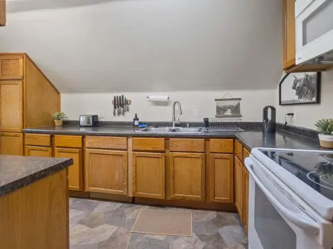 L-shaped kitchen counters with a sink and a white range