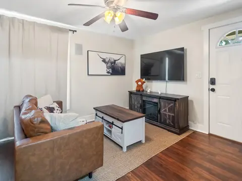 Living room with a leather chair, a TV console, and the front door