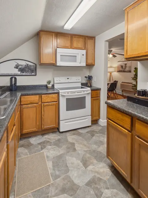 Kitchen with wood cabinets, a white range, and a microwave