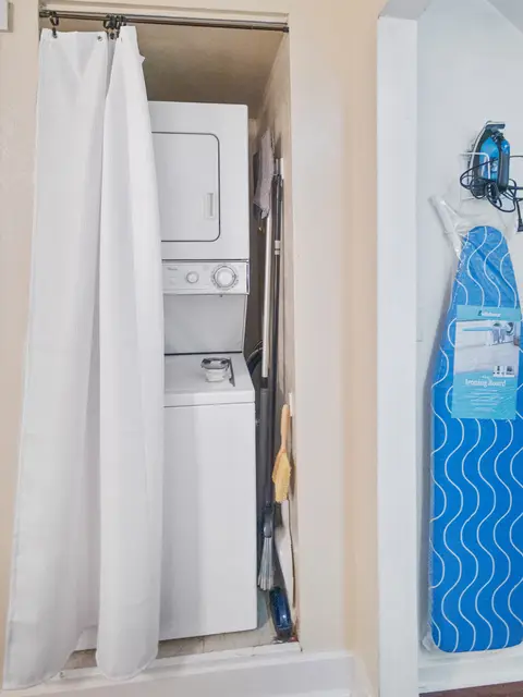 Stacked washer and dryer beside an ironing board