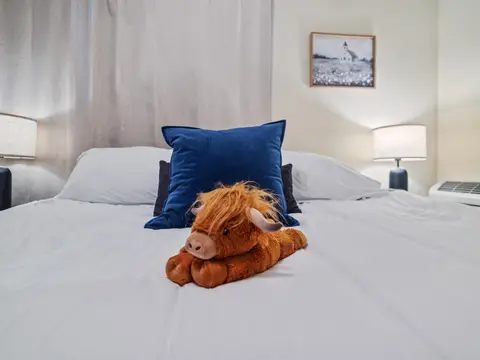 King bed with a navy pillow and a plush highland cow