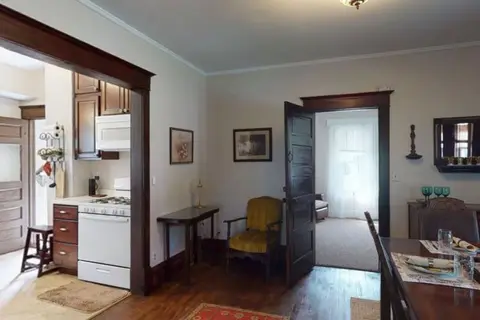 Kitchen seen from the dining room, with a white range and a door to a sitting nook