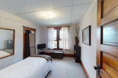 Bedroom with a twin bed, a plaid throw, a small TV, and a wall mirror