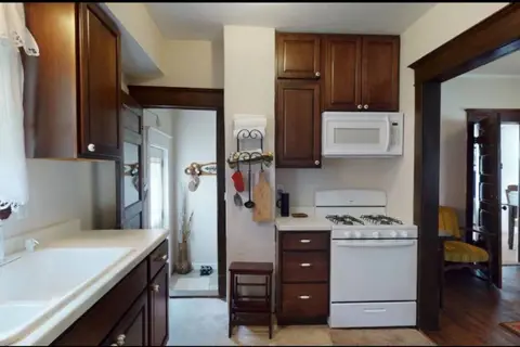 Kitchen with dark wood cabinets, a white gas range, and a microwave above it