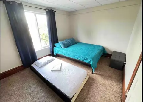 Bedroom with a teal-covered bed and a low twin-size bed made up with white sheets