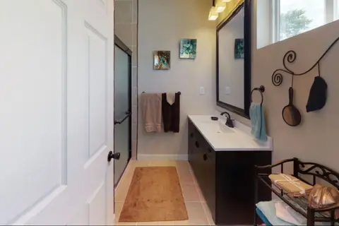 Bathroom with a dark vanity, a wall mirror, and a glass shower door