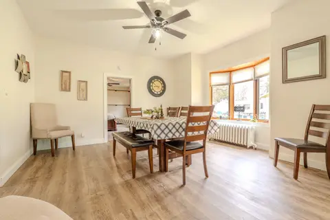 Dining table with a checked cloth, wood chairs, and a bay window