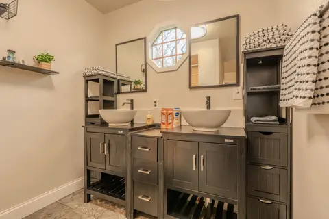 Bathroom with two vessel sinks, two mirrors, and an octagon window