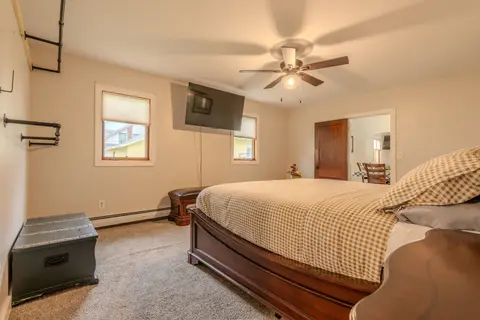 King bedroom with a wall-mounted TV, a storage bench, and pipe clothing racks