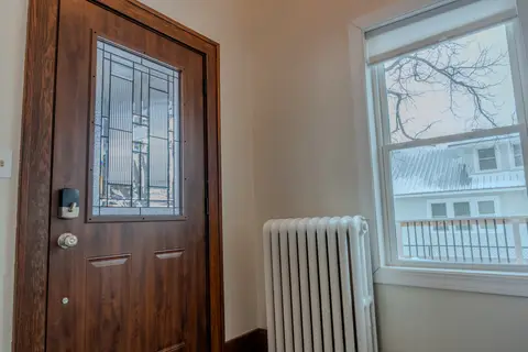 Front door with a leaded glass window beside a radiator