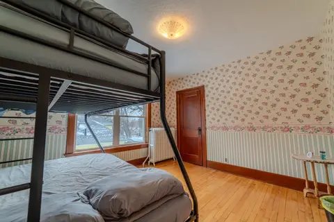 Twin-over-full bunk bed and a window in a wallpapered bedroom