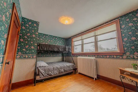 Bunk room with a twin-over-full bunk bed, green floral wallpaper, and a radiator