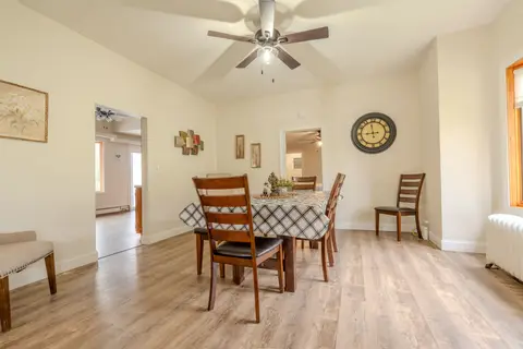 Dining table with a checked tablecloth and wood chairs under a ceiling fan