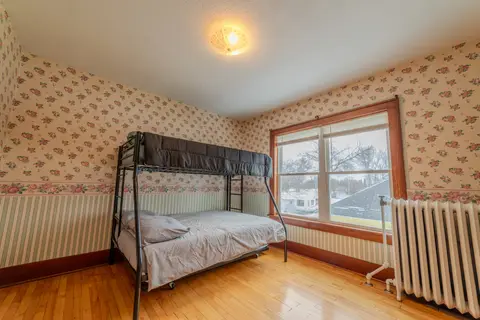 Bunk room with a twin-over-full bunk bed, floral wallpaper, and a radiator