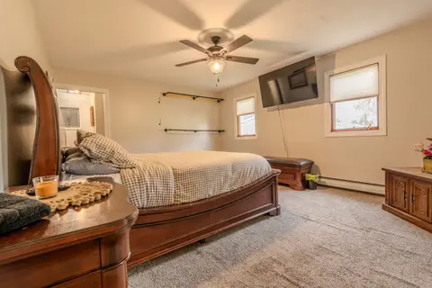 King bed with checked bedding, a wall-mounted TV, and a ceiling fan