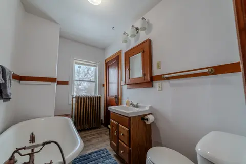 Bathroom with a clawfoot tub, a wood vanity, and a radiator under the window
