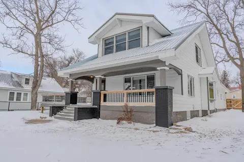 Covered front porch with brick columns and wide steps, in winter