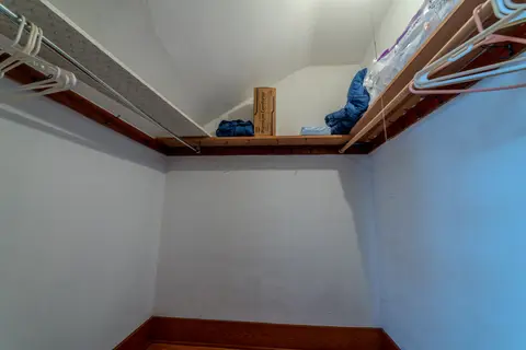Closet under a sloped ceiling with a shelf and a hanging rod