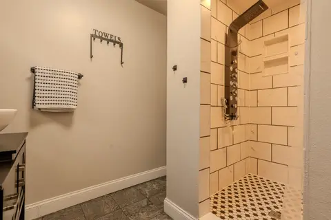 Walk-in shower with white tile walls and a black-and-white tile floor