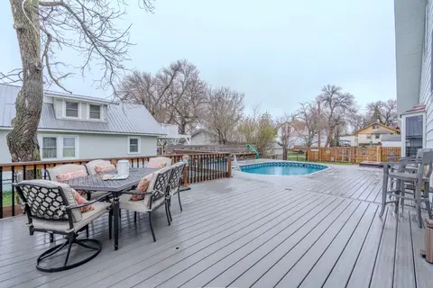 Back deck with an outdoor dining table, a round pool, and a covered hot tub by the fence