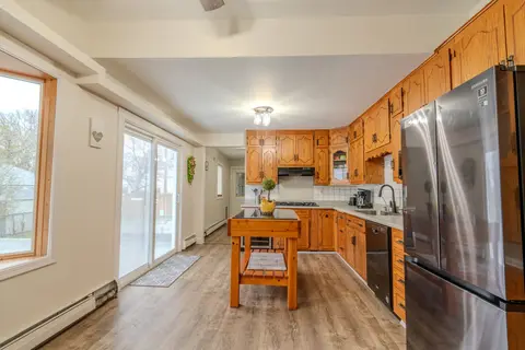 Kitchen with oak cabinets, a butcher-block island, a stainless refrigerator, and a sliding glass door